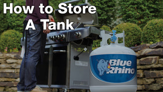 A fresh blue Rhino tank sitting on a patio, with a man grilling at a standup propane grill in the background.